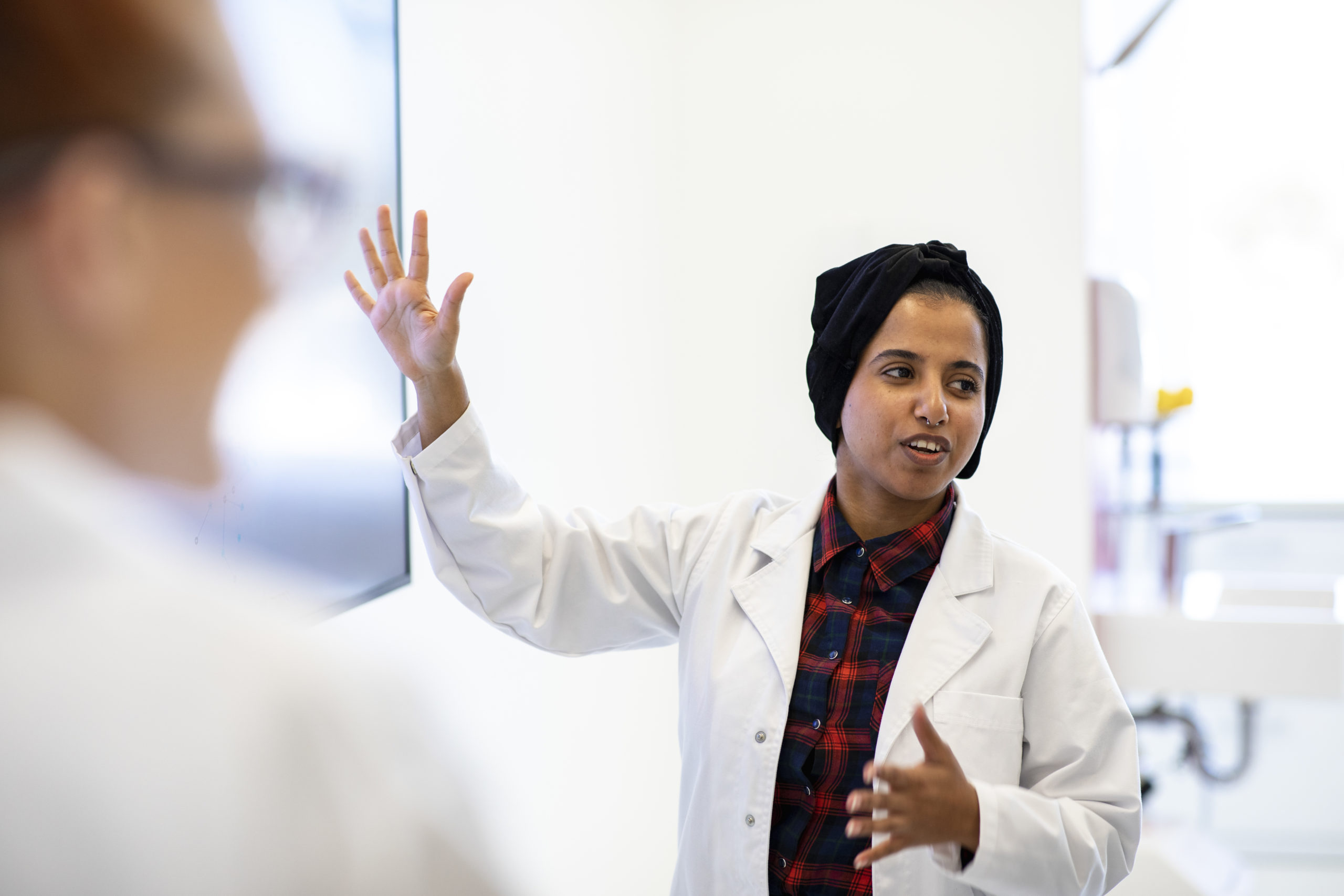 Image of young person lecturing in lab coat